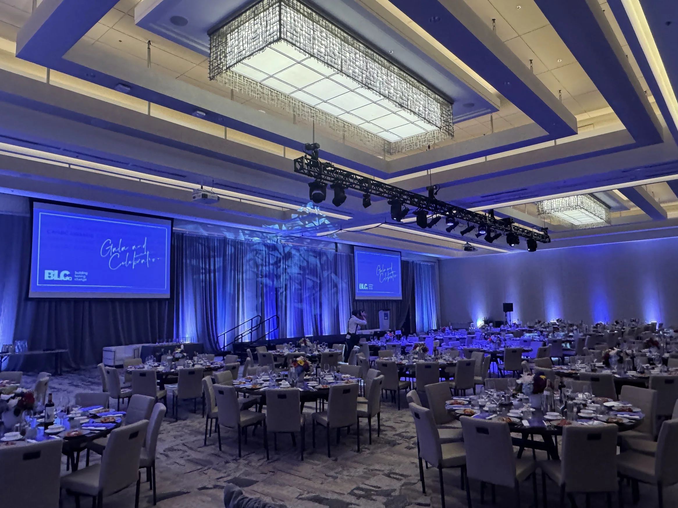 A gala dinner in a ballroom with dramatic blue lighting